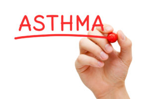 Image of a person's hand writing the word asthma